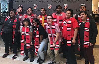 TRIO students standing in front of an SXU backdrop with their stoles