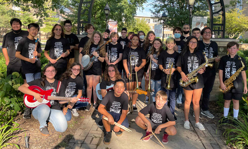 Students at the jazz camp gathered by the SXU Arch with their instrutments, smiling